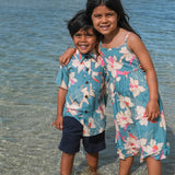 little boy wearing a teal aloha shirt with cream colored orchid blossom pattern