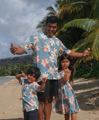 man wearing a teal aloha button up shirt with cream colored orchid pattern