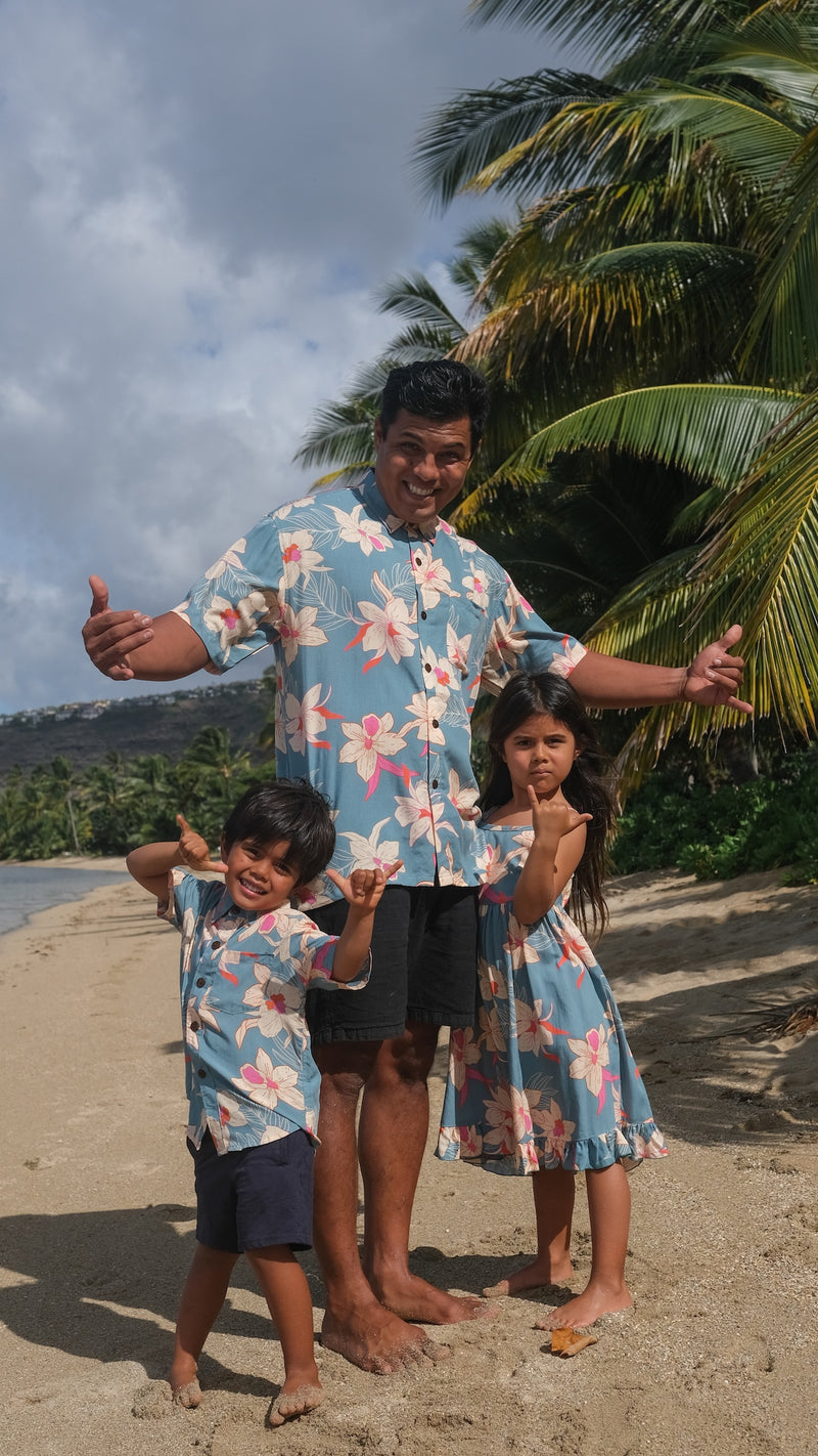 man wearing a teal aloha button up shirt with cream colored orchid pattern
