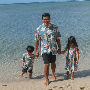 little boy wearing a teal aloha shirt with cream colored orchid blossom pattern