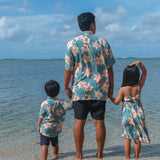man wearing a teal aloha button up shirt with cream colored orchid pattern