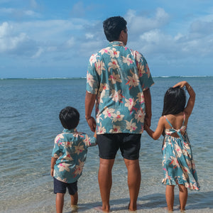 man wearing a teal aloha button up shirt with cream colored orchid pattern