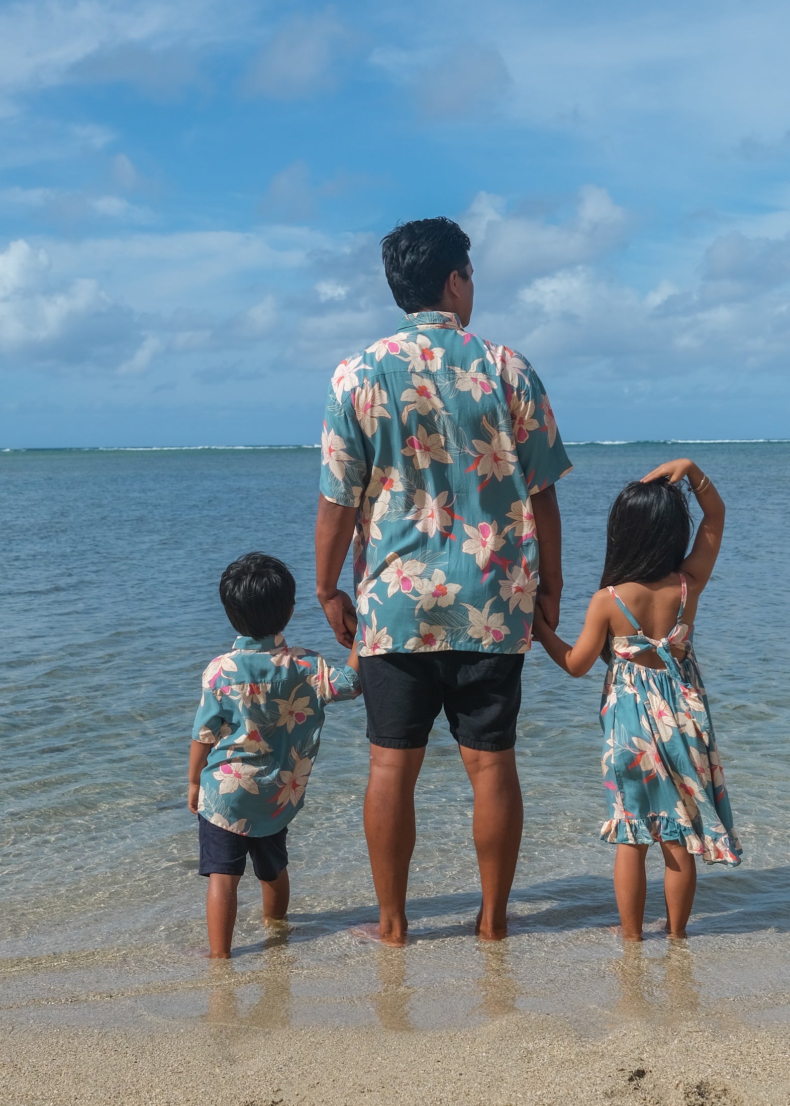 man wearing a teal aloha button up shirt with cream colored orchid pattern