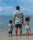 man wearing a teal aloha button up shirt with cream colored orchid pattern