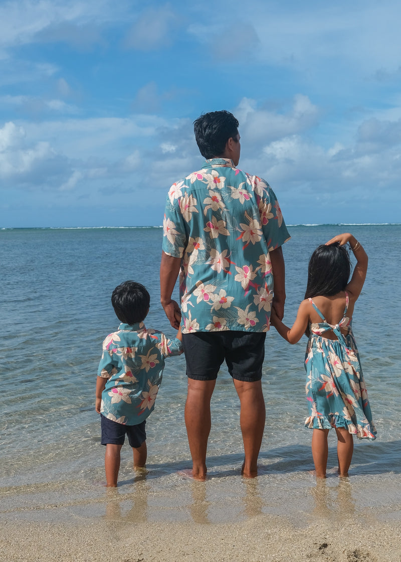 man wearing a teal aloha button up shirt with cream colored orchid pattern