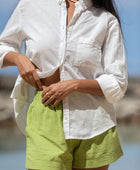 The YIREH A La Mode Button-Up in Cloud is a linen, slightly oversized, long-sleeve button-up featuring mother-of-pearl shell buttons. -w/ Parakeet Millie Short
