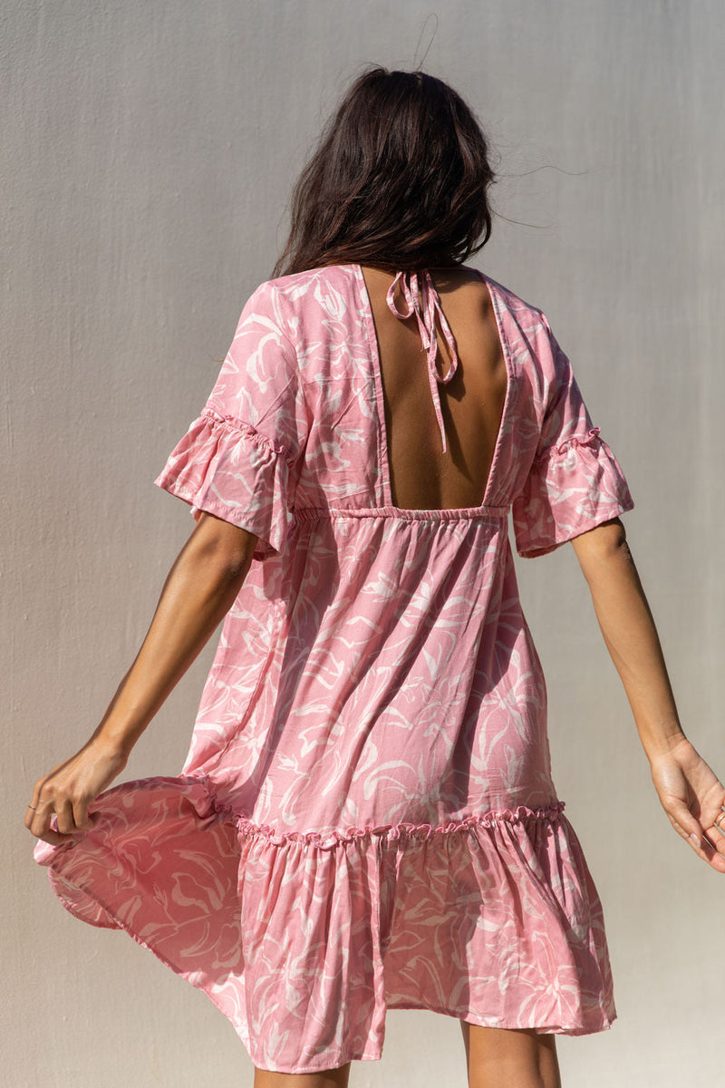 The Yireh Ariana Dress in petal. Romantic and feminine silhouette. This is a versatile style featuring an elastic waist, ruffle hem and flutter sleeves. Open back with a tie around the shoulders. Ethically and sustainably made featuring a one of a kind and exclusive print.