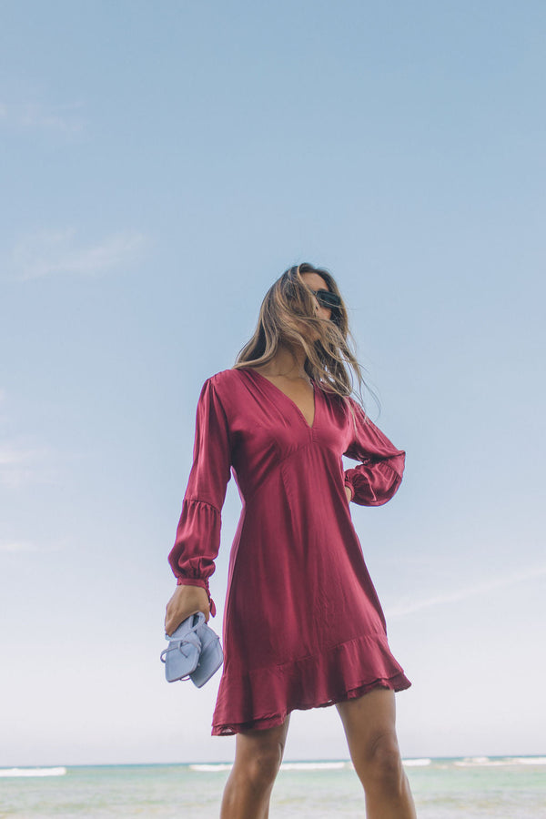 The Yireh Aster Dress in berry. Romantic and feminine silhouette. This is a classic Yireh style featuring flowing sleeves with a tie at the wrist and a zipper closure in back. Part of our limited run of solids, perfect to transition from day to night. Ethically and sustainably made resort wear.
